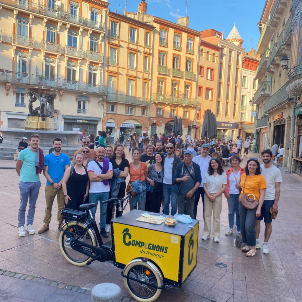 Groupe de collaborateurs en visite dans un lieu emblématique toulousain (Capitole, Cité de l'Espace, bords de Garonne), guide au premier plan, atmosphère découverte et curiosité.